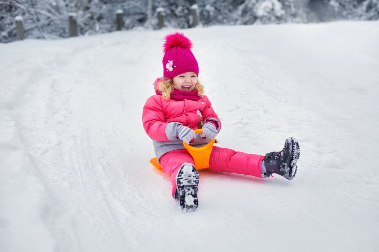 girl sledding as a holiday activity with her family